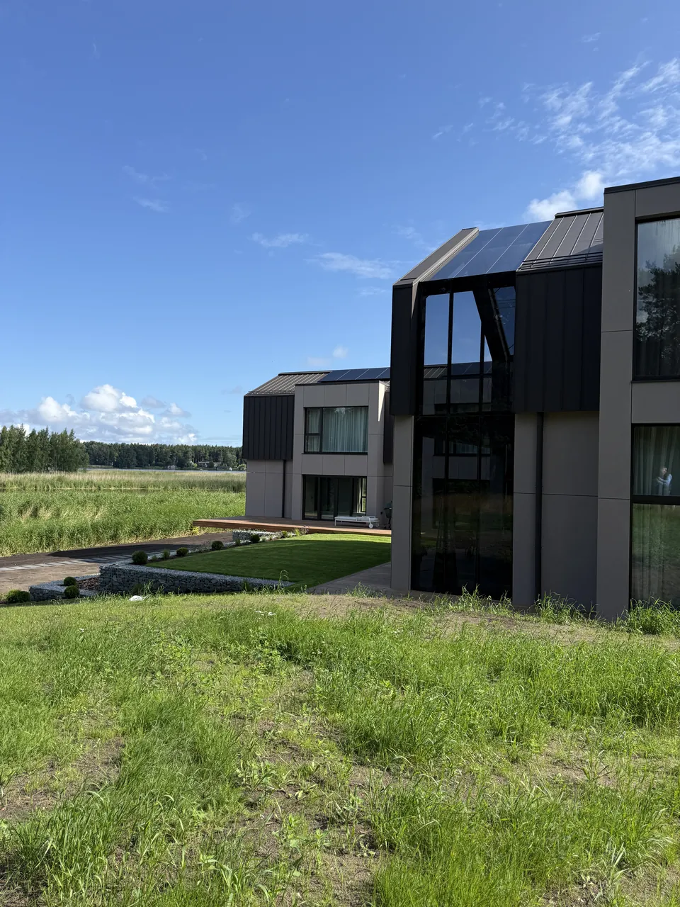 Mūsdienīga divstāvu ēka ar tumšu apdari un lielām stiklotām fasādēm