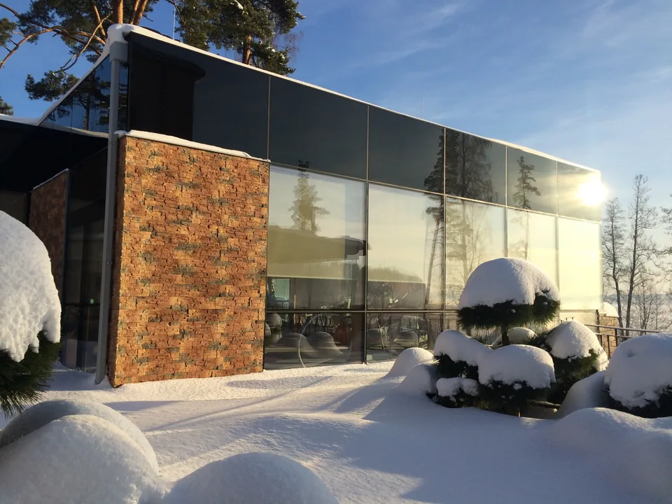 Glazed facade beside a stone-clad wall and a snow-covered courtyard
